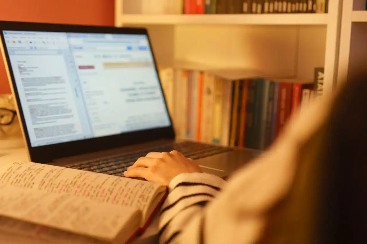Consulta de documentos en una laptop junto a apuntes de estudio