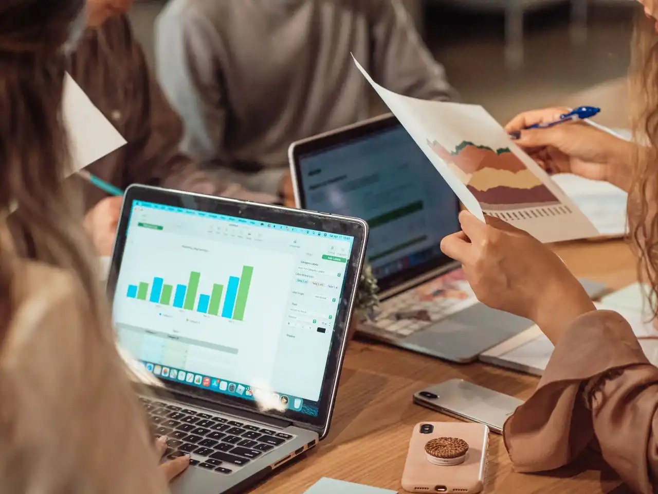Grupo revisando una gráfica de barras en una laptop y una gráfica impresa